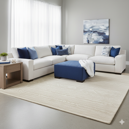 Modern living room with a white sectional sofa, blue ottoman, and decorative pillows.